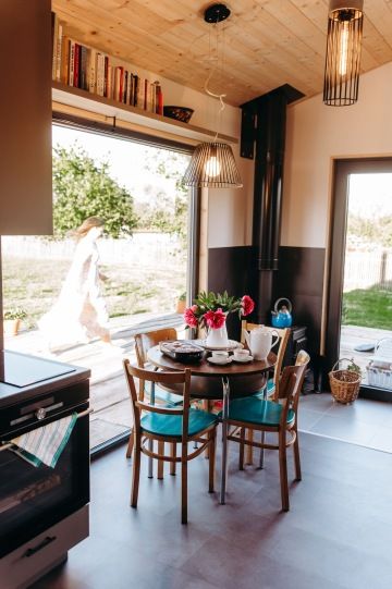 Pohled na prostřený jídelní stůl s krásným výhledem na louku velkým proskleným oknem v tiny housu v nádechu.