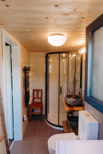 Moderní koupelna s dřevěnými detaily a umyvadlem z kamene z Bali v tiny housu v nádechu.