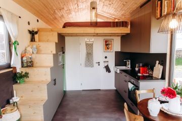 Ukázka prostorného a moderního interiéru tiny house, včetně kuchyně a spací plochy v glampingu nádech.