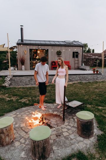 Mladý pár si opéká špekáčky na ohništi před tiny housem v nádechu v Děkanovicích.