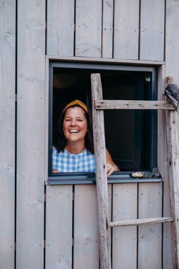 Usměvavá žena vykukující z dřevěného okna na statku nádech.