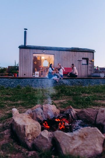 Uhasínající oheň a přátelé u tiny housu ve večerním světle v nádechu.