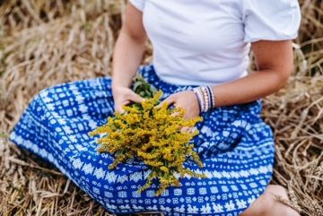 Žena drží luční květinu v dlaních – symbol klidu, jednoduchosti a spojení s přírodou v nádechu.